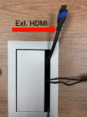 An image showing an HDMI cable coming out of a conference room table. The cable is labeled 